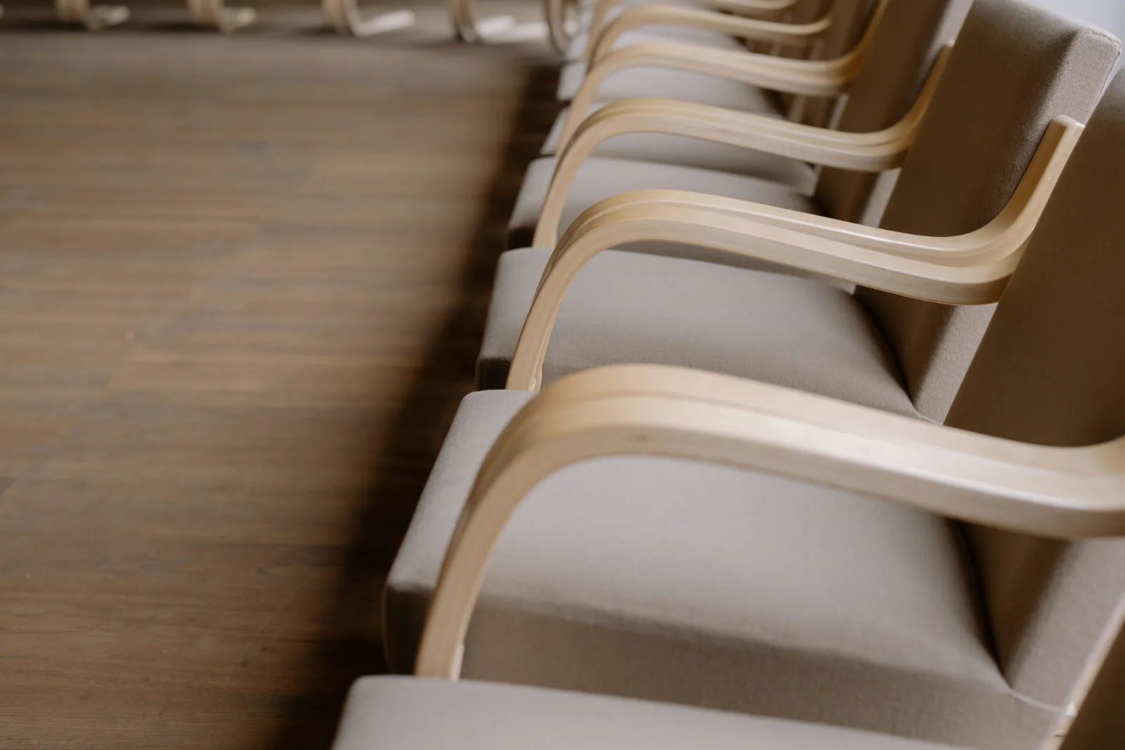 A row of empty wooden armchairs in a quiet meeting room